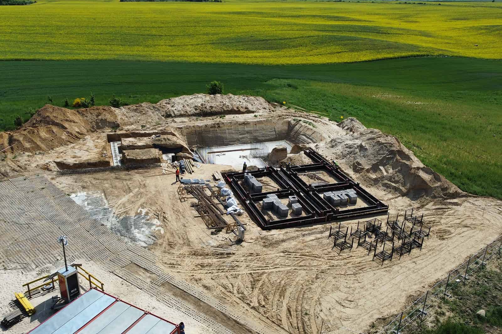 Widok z góry na wykop, ławy fundamentowe i zaplecze budowy